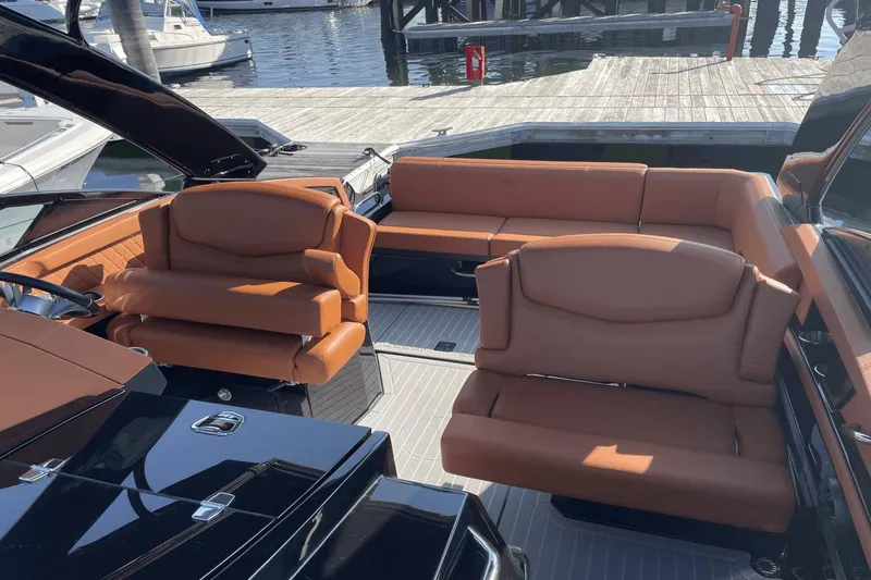 Slide: The Image of 2021 Cruisers Yachts 338 CX interior with brown leather seating at marina. - 8