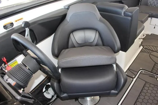 Slide: The Image of 2023 Scarab 255 ID boat interior with black captain's chair and steering wheel. - 2