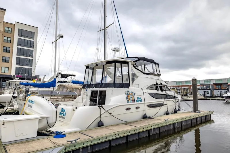 Slide: The Image of 2004 Meridian 459 Motoryacht docked at marina, overcast sky, modern buildings in background. - 2