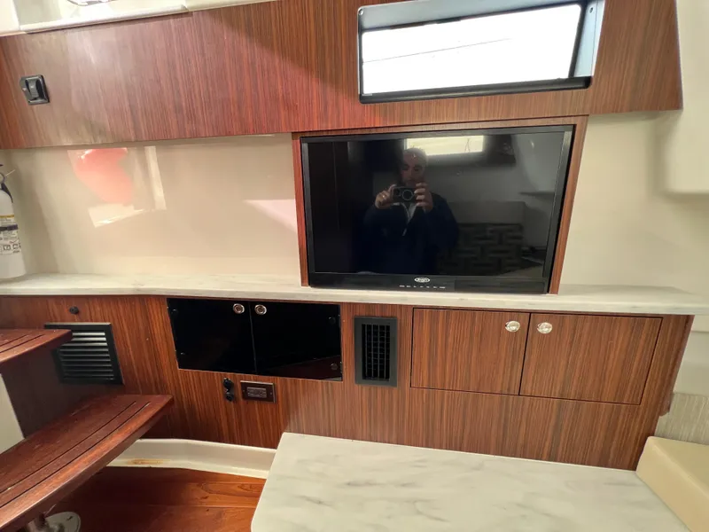 Slide: The Image of Interior of 2022 Pursuit S 358 boat with wood paneling and mounted TV. - 26