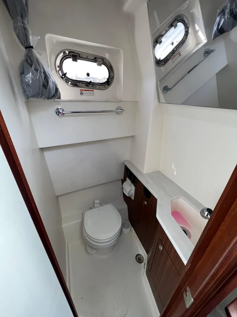 Slide: The Image of 2022 Pursuit S 358 boat bathroom with toilet, sink, and porthole window. - 31