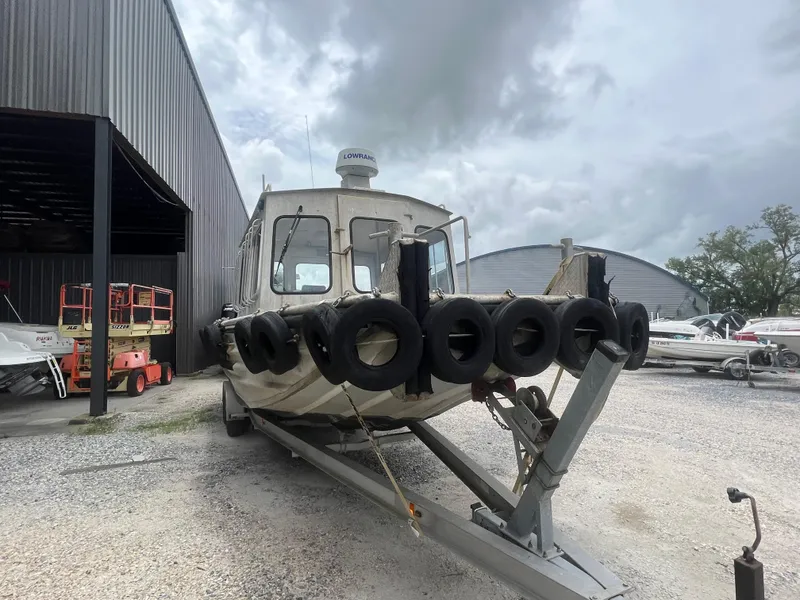 Slide: The Image of Custom Flat 28 Cabin Boat 2010 on trailer, surrounded by tires, parked near storage facility. - 7