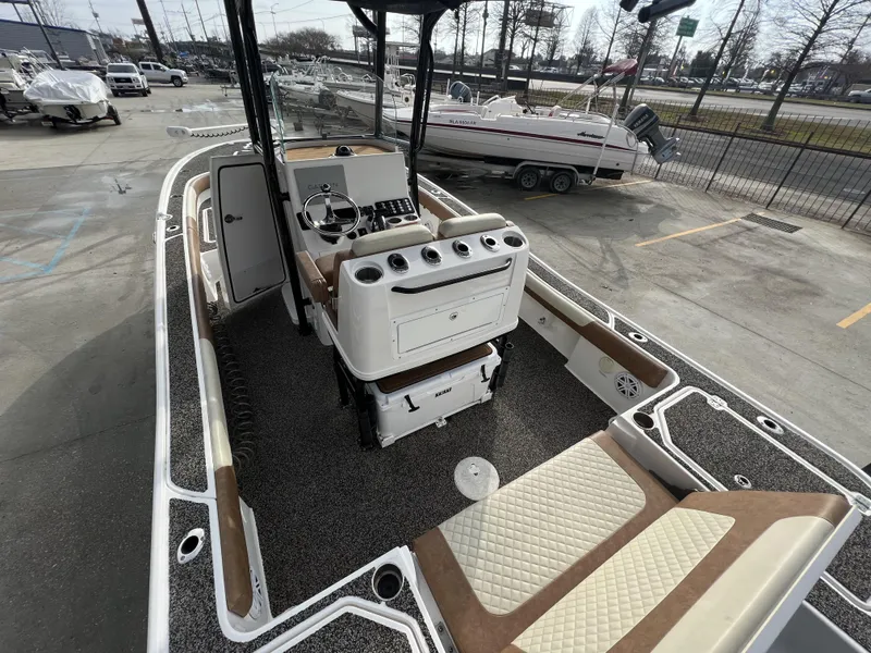 Slide: The Image of 2021 Caymas 26 HB boat interior with seating and control panel, parked in a marina. - 10