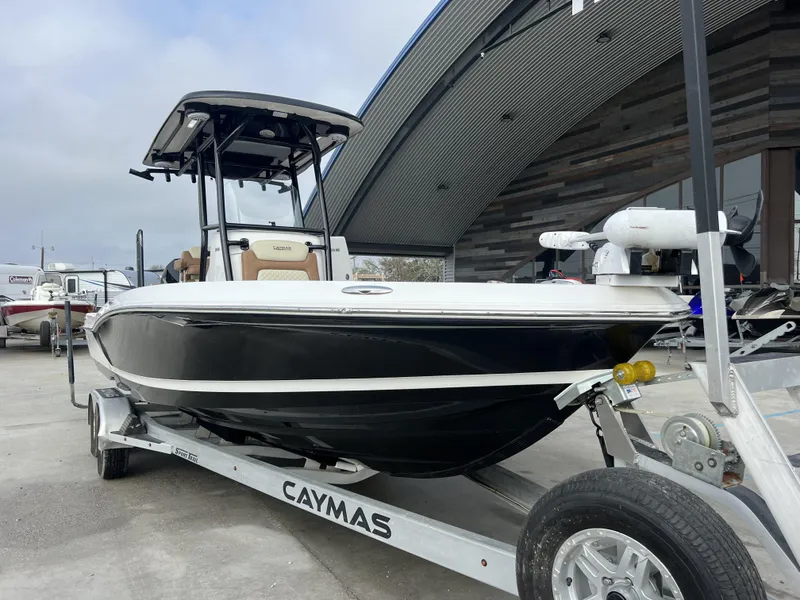 Slide: The Image of 2021 Caymas 26 HB boat on trailer, parked outside a modern building. - 14