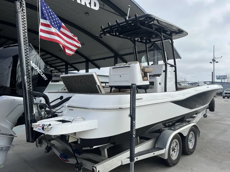 Slide: The Image of 2021 Caymas 26 HB boat on trailer with American flag, parked outdoors. - 20