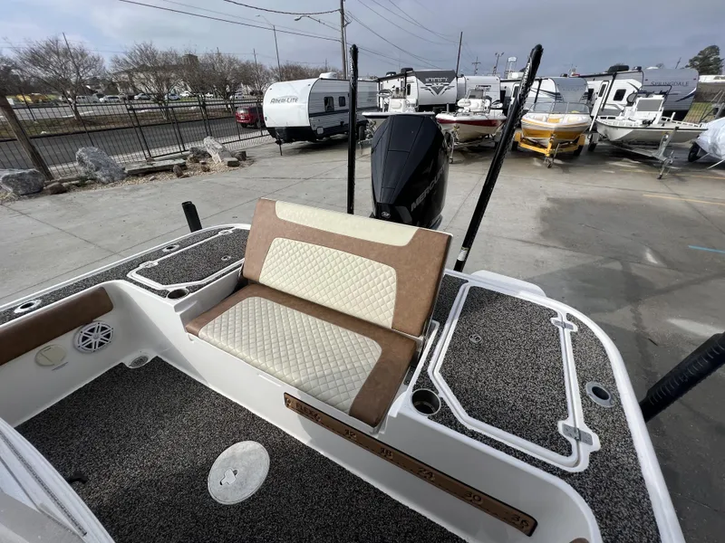 Slide: The Image of 2021 Caymas 26 HB boat interior with cushioned seating and Mercury engine in a dealership lot. - 22