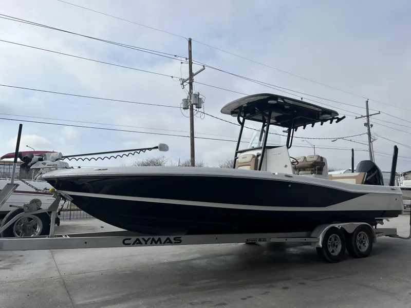 Slide: The Image of 2021 Caymas 26 HB boat on trailer, displayed outdoors under cloudy sky. - 4