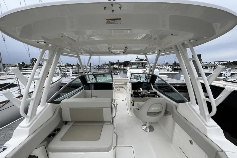 Slide: The Image of 2022 Boston Whaler 240 Vantage boat interior at a marina, featuring seating and helm station. - 21