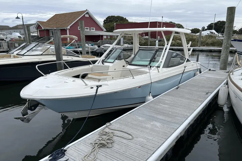 Slide: The Image of 2022 Boston Whaler 240 Vantage docked at marina with red building in background. - 25