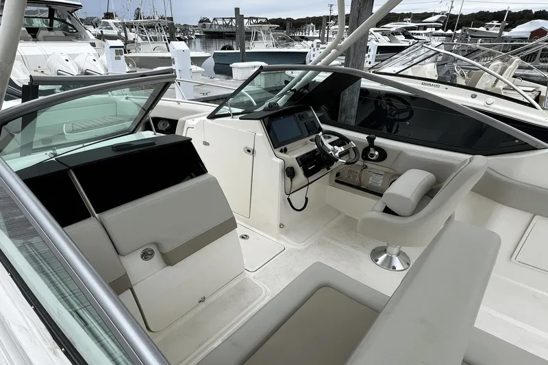 Slide: The Image of 2022 Boston Whaler 240 Vantage boat interior with helm station and seating at marina. - 7