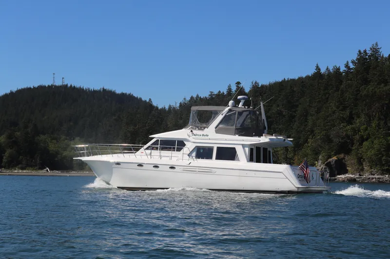 Slide: The Image of 2000 Navigator 5300 yacht cruising on a scenic lake with forested hills. - 0