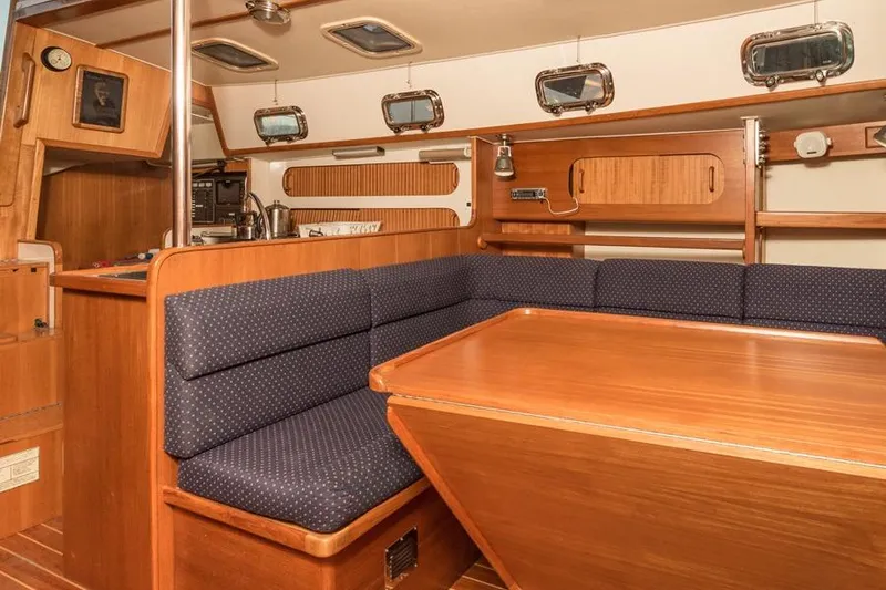 Slide: The Image of Interior of a 2002 Caliber 40 sailboat with wooden furnishings and blue seating. - 19