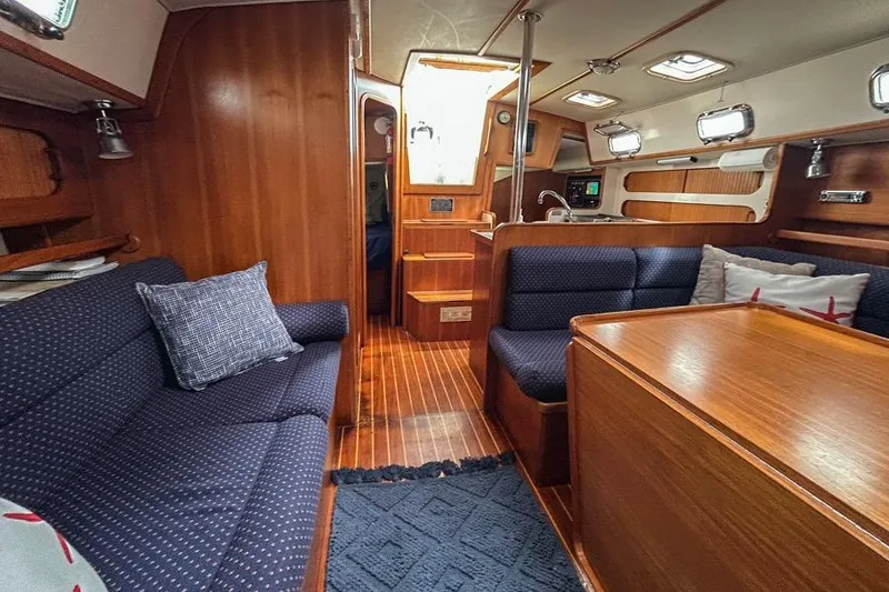 Slide: The Image of Interior of 2002 Caliber 40 sailboat with wooden furnishings and blue seating. - 9