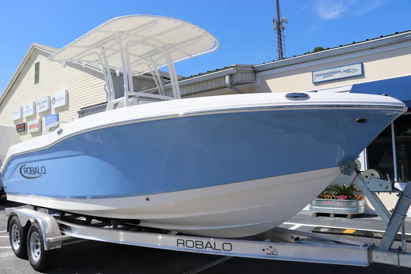 Slide: The Image of 2024 Robalo R202 EX boat on a trailer outside a dealership. - 2