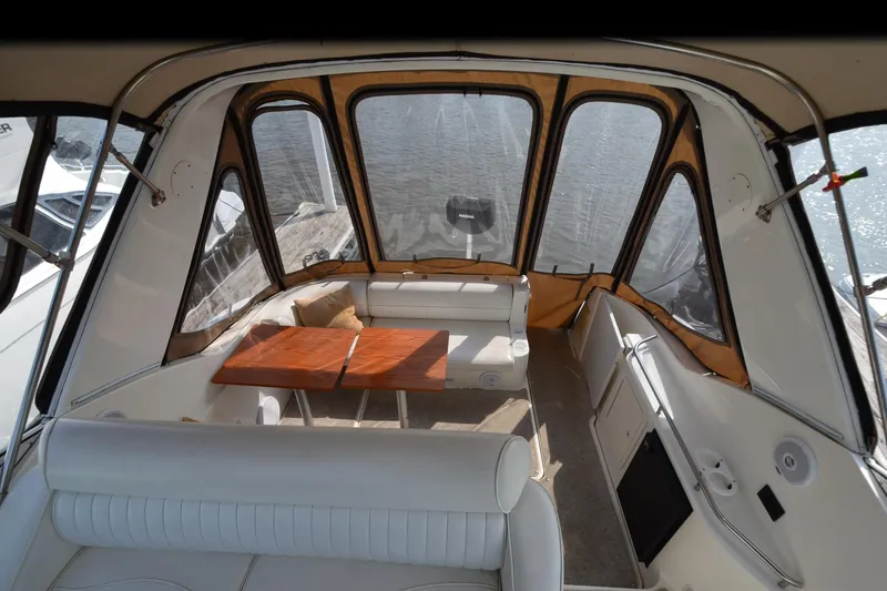 Slide: The Image of 2004 Cruisers Yachts 320 Express interior with seating and table, docked by the water. - 10