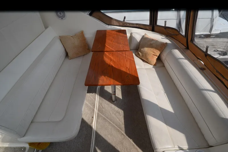 Slide: The Image of 2004 Cruisers Yachts 320 Express interior with white seating and wooden table. - 12