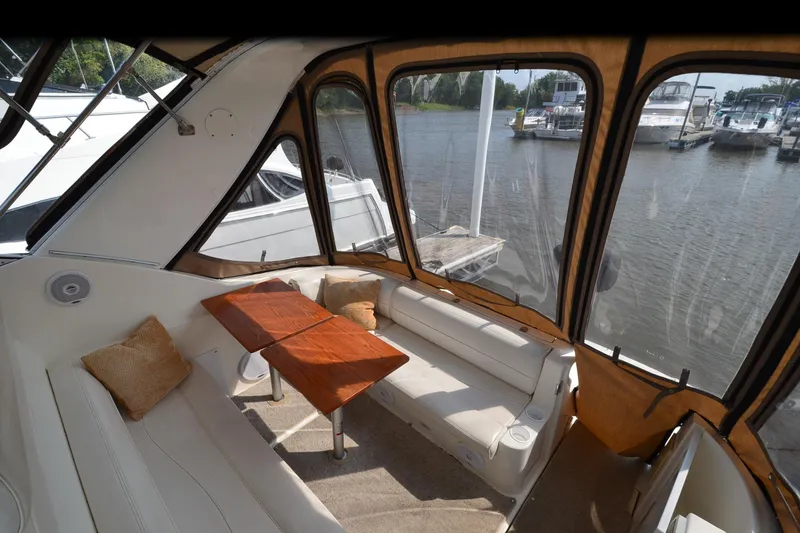 Slide: The Image of 2004 Cruisers Yachts 320 Express interior with seating and table, overlooking marina. - 13