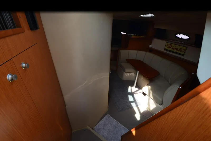 Slide: The Image of 2004 Cruisers Yachts 320 Express interior with cozy seating and wooden cabinetry. - 18