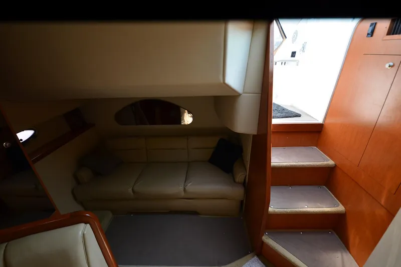 Slide: The Image of 2004 Cruisers Yachts 320 Express interior with beige sofa and wooden stairs. - 19