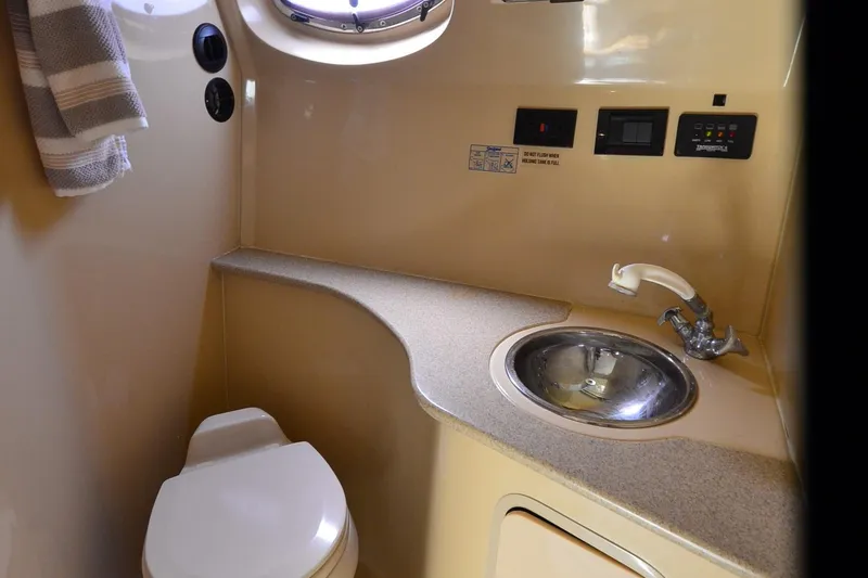 Slide: The Image of 2004 Cruisers Yachts 320 Express bathroom with sink, toilet, and porthole window. - 21
