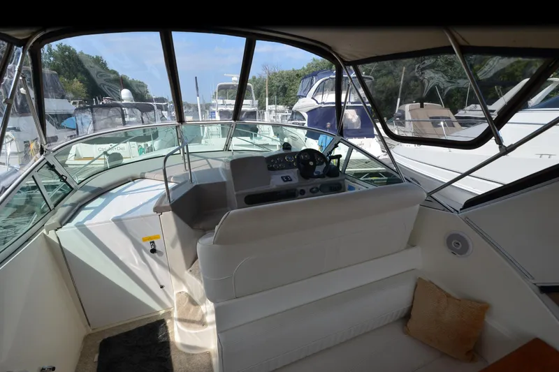 Slide: The Image of 2004 Cruisers Yachts 320 Express cockpit with helm, marina view, and comfortable seating. - 7