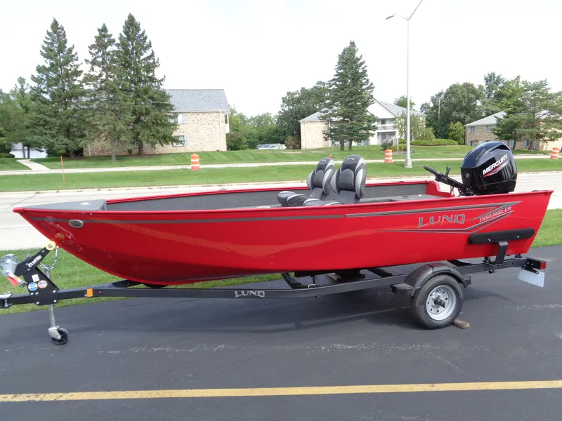 The Image of 2024 Lund 1650 Angler boat in vibrant red on a trailer, parked outdoors. - 0
