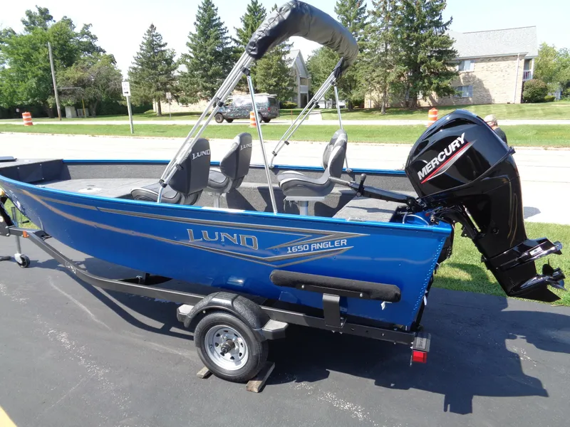 The Image of 2024 Lund 1650 Angler boat with Mercury engine on trailer, parked outdoors. - 0