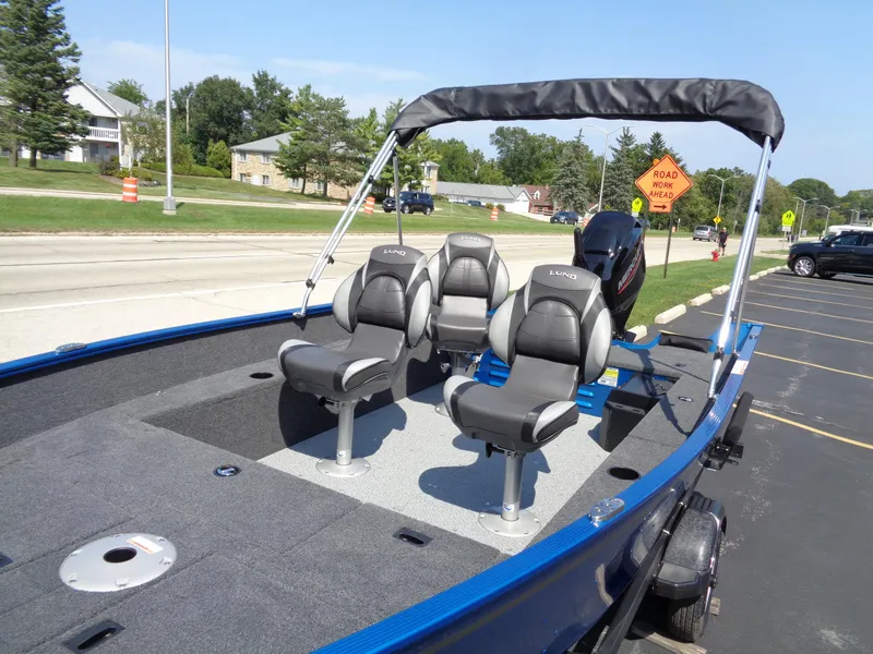 Slide: The Image of 2024 Lund 1650 Angler boat with seating, parked on a sunny street. - 6