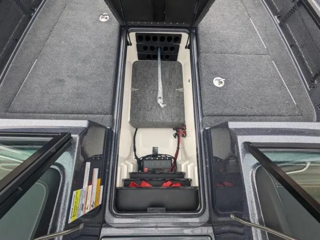 Slide: The Image of 2025 Lund 219 Pro-V GL boat interior with storage compartments and fishing rod holders. - 6