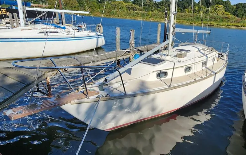 Slide: The Image of 1980 Cape Dory 30 sailboat docked at a marina, surrounded by calm water. - 0