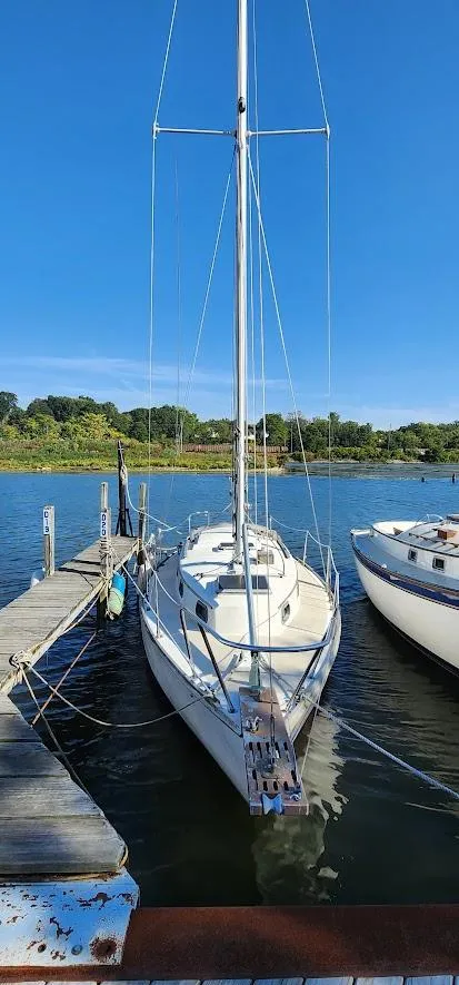 Slide: The Image of 1980 Cape Dory 30 sailboat docked on a sunny day, surrounded by calm water. - 1