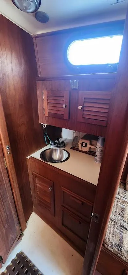 Slide: The Image of 1980 Cape Dory 30 sailboat interior with wooden cabinetry and stainless steel sink. - 10