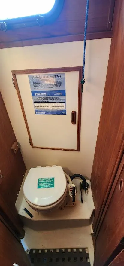 Slide: The Image of 1980 Cape Dory 30 sailboat bathroom with compact marine toilet and wooden cabinetry. - 12