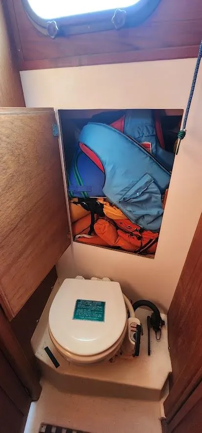 Slide: The Image of 1980 Cape Dory 30 sailboat bathroom with storage compartment and marine toilet. - 13