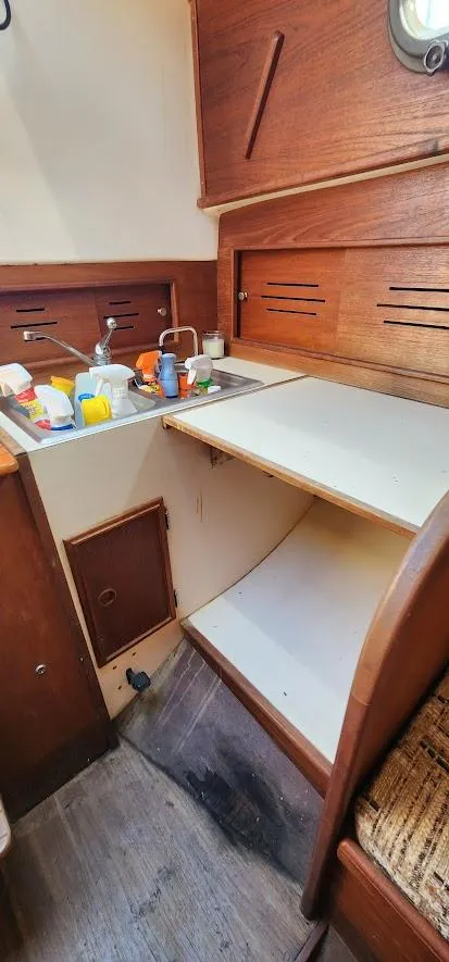 Slide: The Image of 1980 Cape Dory 30 sailboat interior with wooden cabinetry and compact kitchen area. - 21