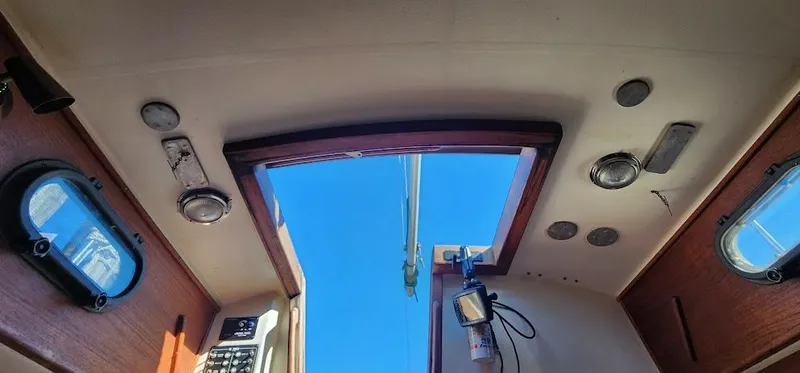 Slide: The Image of Interior view of a 1980 Cape Dory 30 sailboat, featuring a skylight and wooden paneling. - 23