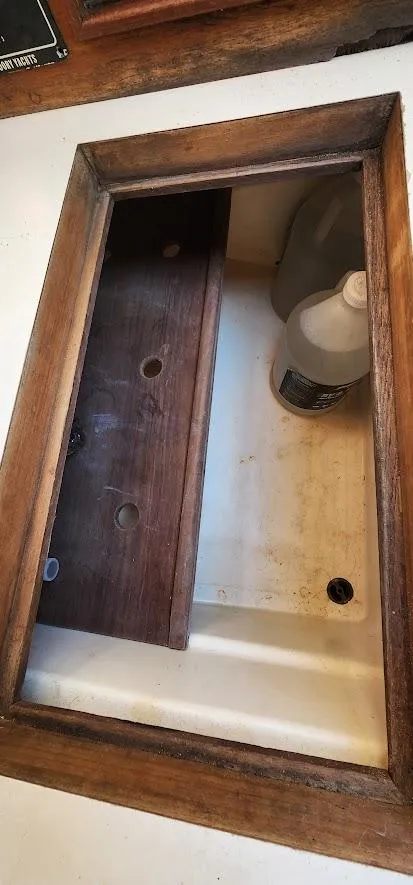 Slide: The Image of Wooden-framed compartment on a 1980 Cape Dory 30 sailboat, featuring storage space and cleaning supplies. - 24