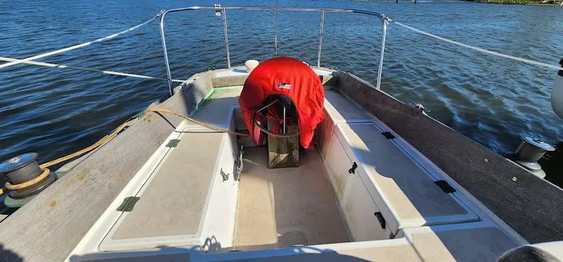 Slide: The Image of 1980 Cape Dory 30 sailboat deck with red cover, docked on calm water. - 25