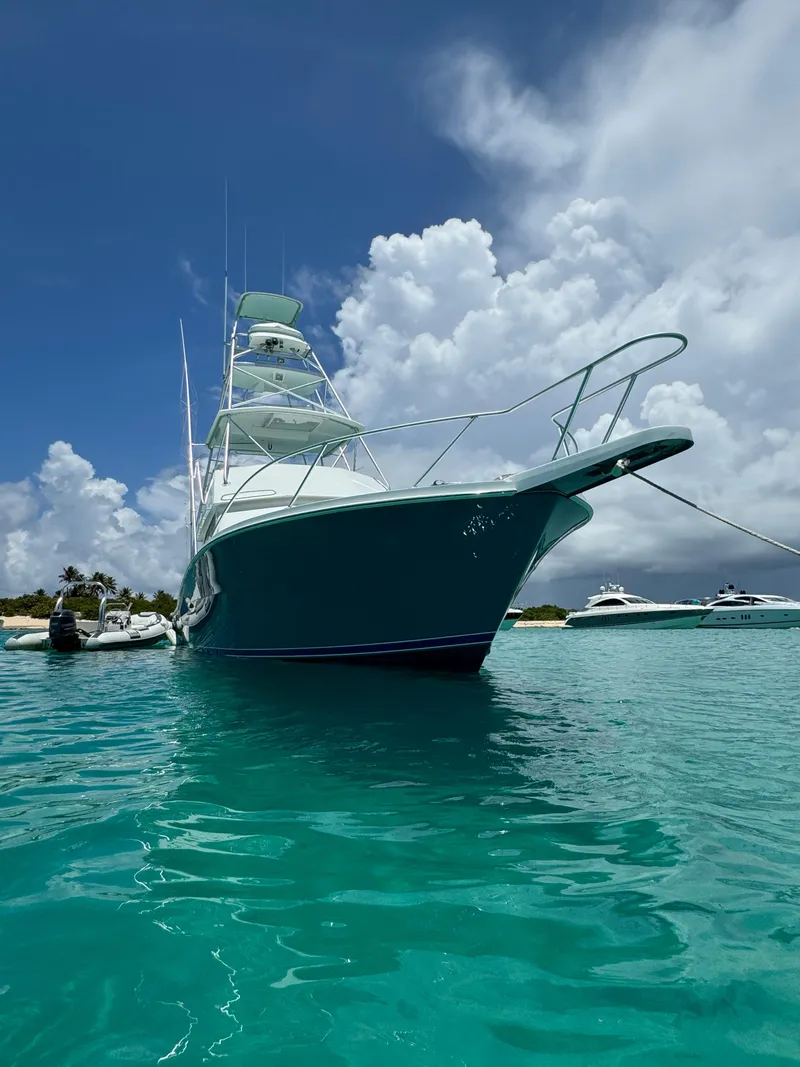 Slide: The Image of 1997 Viking 43 Convertible yacht anchored in clear turquoise water under a partly cloudy sky. - 10