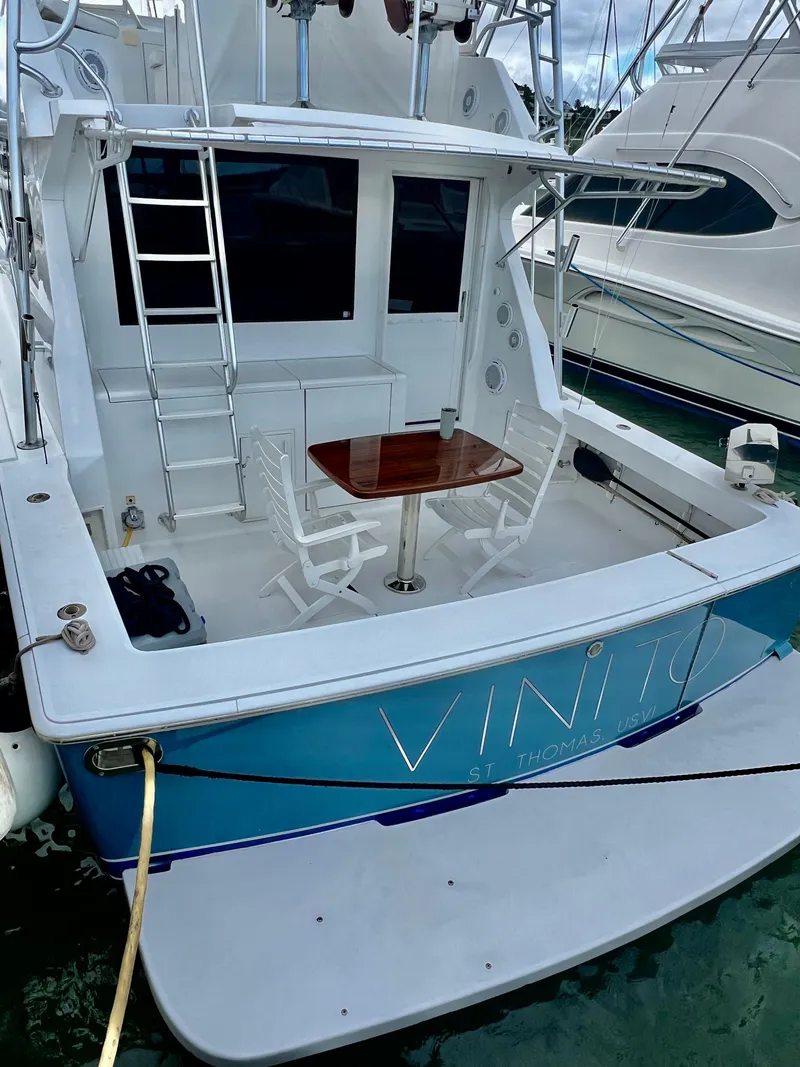 Slide: The Image of 1997 Viking 43 Convertible yacht docked, featuring a rear deck with seating and table. - 42