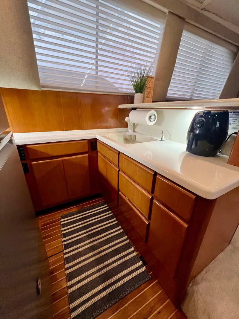 Slide: The Image of 1997 Viking 43 Convertible yacht kitchen with wood cabinets, striped rug, and countertop appliances. - 57