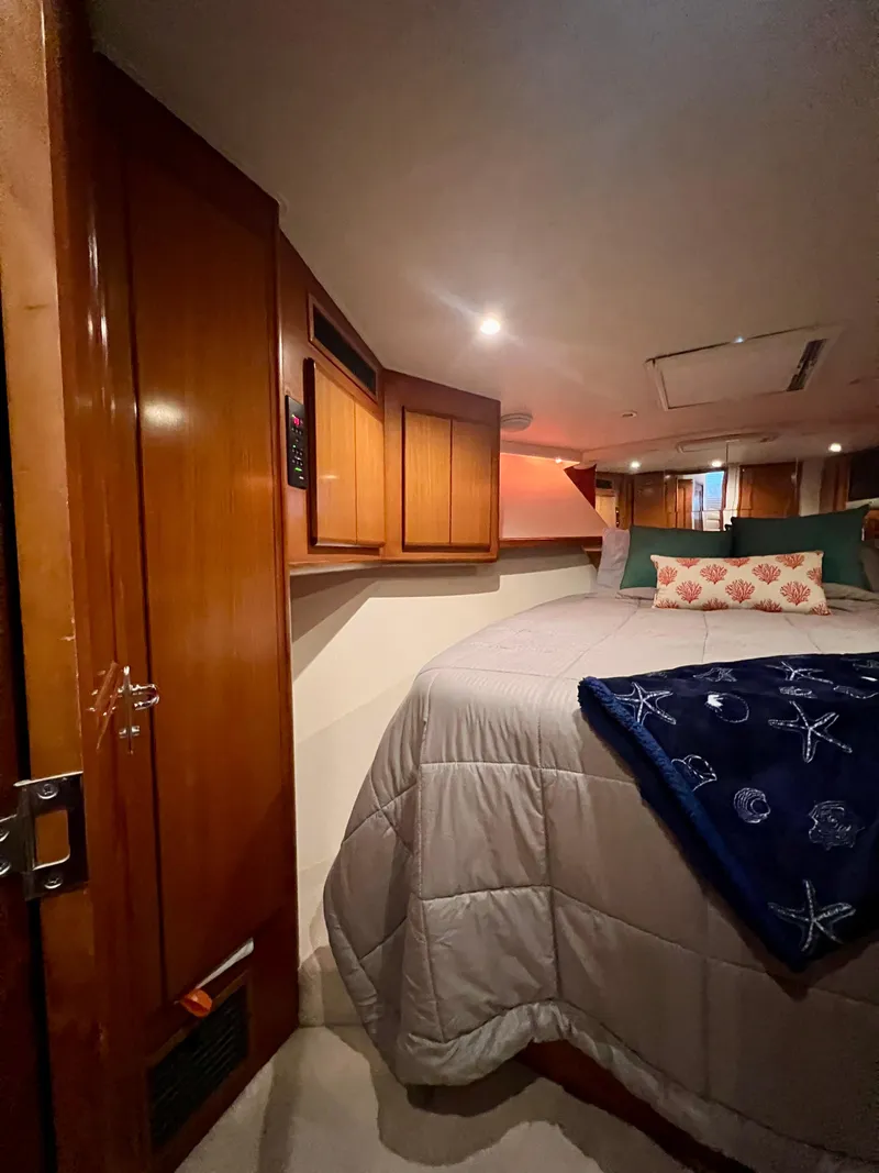 Slide: The Image of Cozy bedroom in a 1997 Viking 43 Convertible yacht with wooden cabinets and soft lighting. - 64