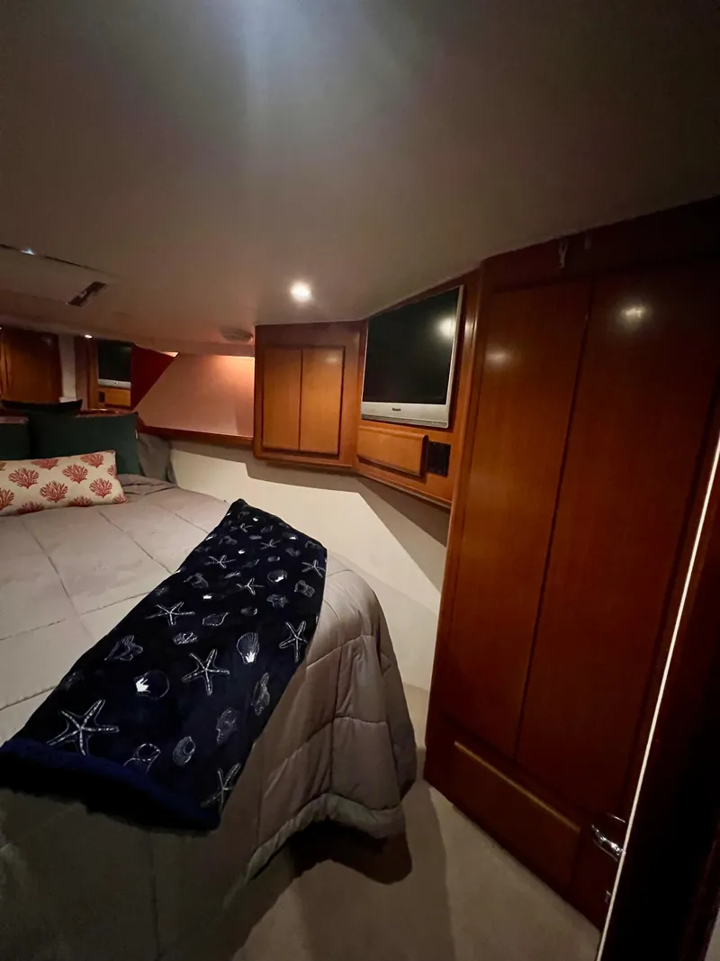 Slide: The Image of Cozy bedroom in 1997 Viking 43 Convertible yacht with wooden cabinets and TV. - 65