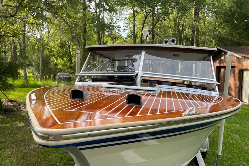 Slide: The Image of 1979 Skiff Craft Hard Top Cruiser with polished wooden deck in a lush green yard. - 1
