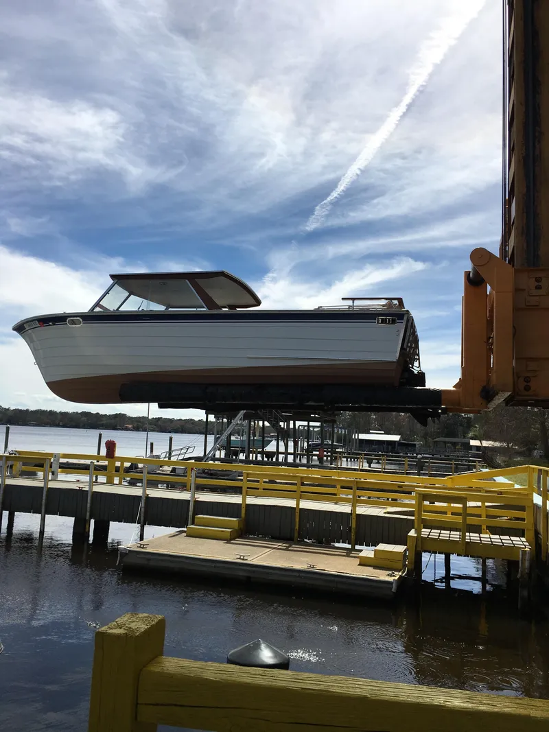 Slide: The Image of 1979 Skiff Craft Hard Top Cruiser being lifted at a dock under a cloudy sky. - 13