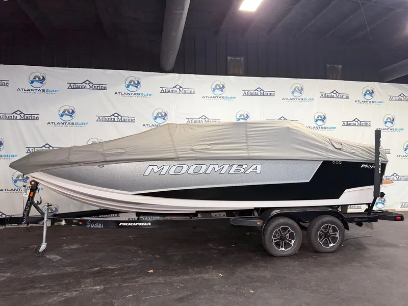 Slide: The Image of A 2024 Moomba Mojo boat on a trailer, covered, inside a showroom. - 30