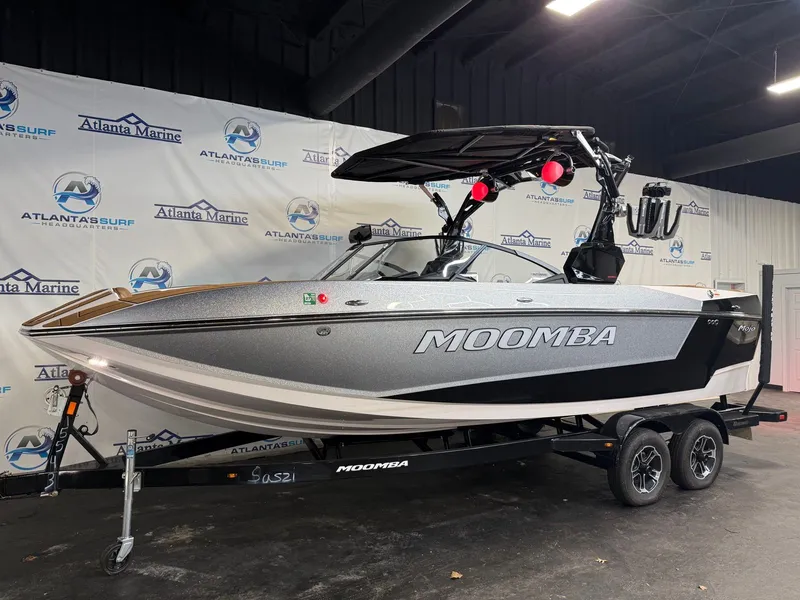 Slide: The Image of A 2024 Moomba Mojo boat on a trailer in a showroom setting. - 2