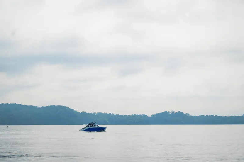 Slide: The Image of 2024 Yamaha Boats 222XD on a calm lake with a forested shoreline. - 33
