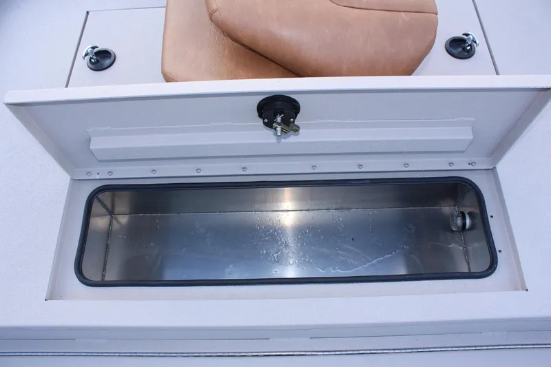 Slide: The Image of 2024 Avid 20 Rogue boat storage compartment with open lid and brown seat. - 35