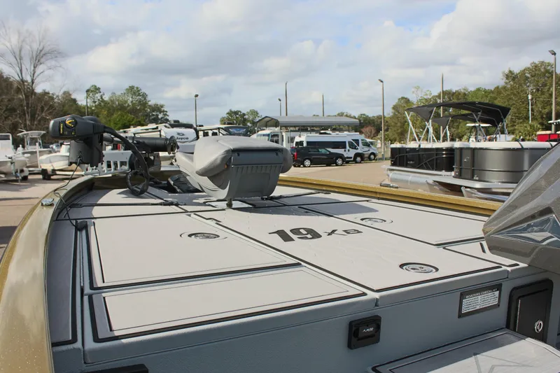 Slide: The Image of 2024 Avid 19 XB boat deck with storage compartments and motor in a marina. - 24